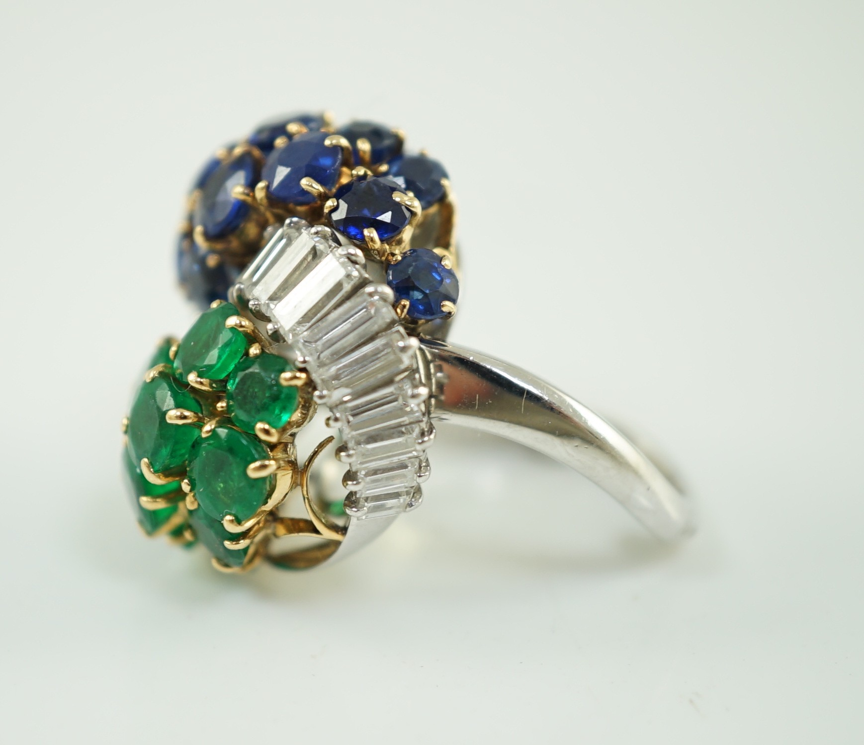 A mid 20th century French 18ct white gold round cut emerald, sapphire and graduated baguette cut diamond cluster set 'Yin-Yang' dress ring, by Mauboussin, Paris